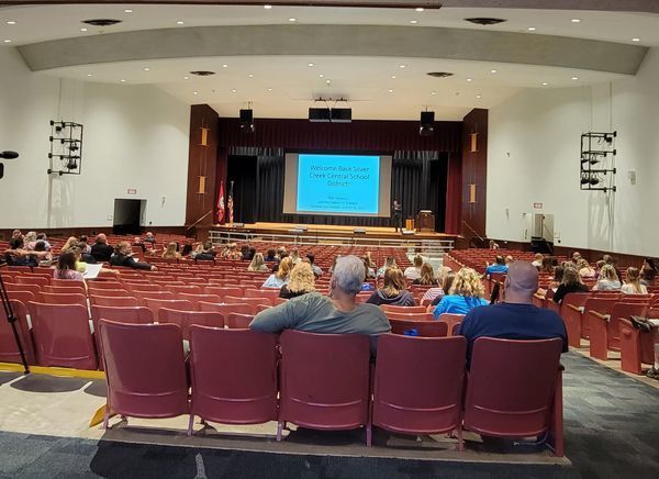 A view of staff seated in the auditorium at Silver Creek from the back of the room facing the screen on stage 