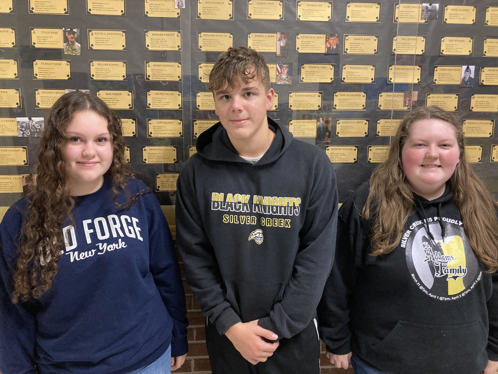 Karissa Buchanan, Michael Dispenza and Harmony Sinders stand in front of one of the sections of the Veterans Tribute Wall at Silver Creek CSD. 