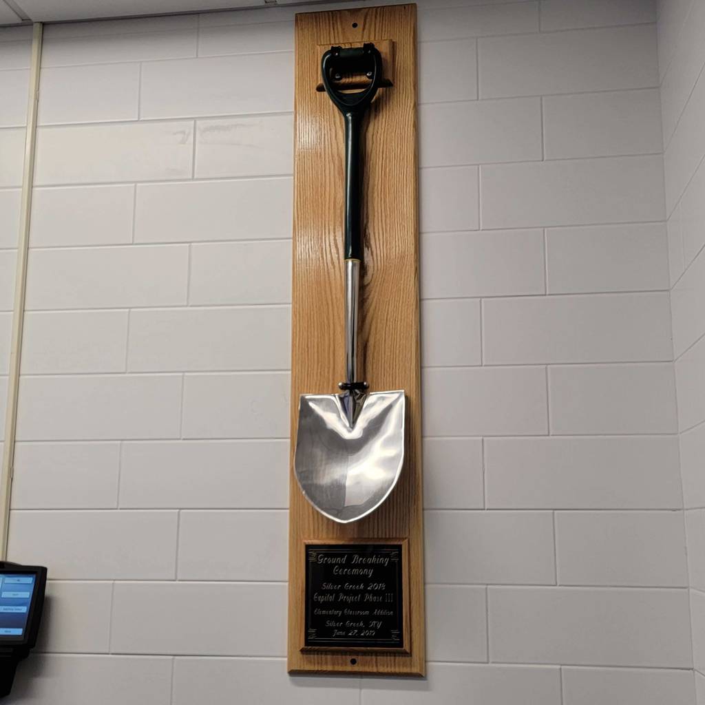 The groundbreaking shovel used for the Capital Project hangs on a wall above a small plaque