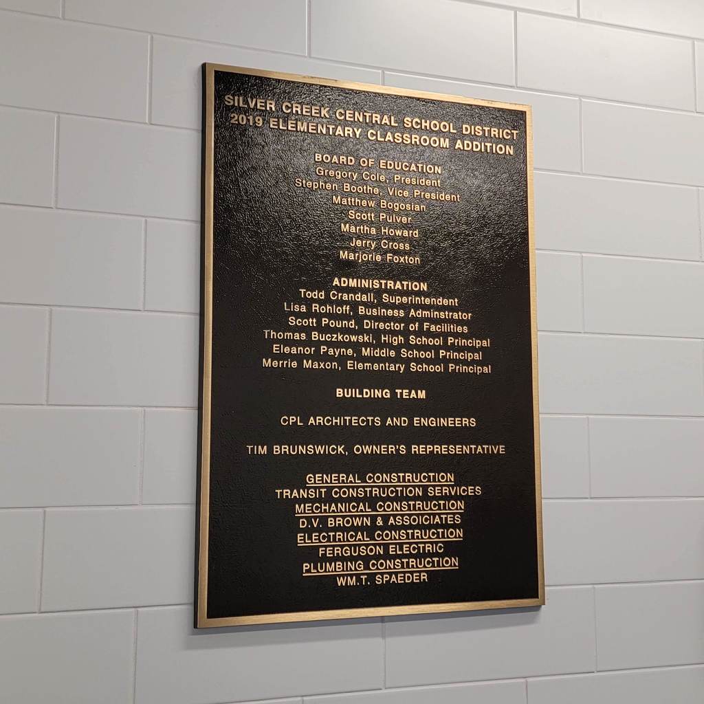 A classroom addition plaque with names of those involved hangs on the wall.