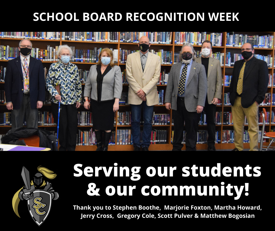 Seven school board members wearing masks stand in a library