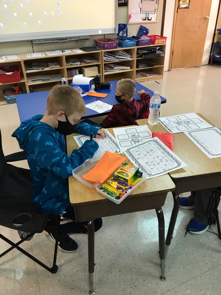 Two students work on a writing assignment at their desks
