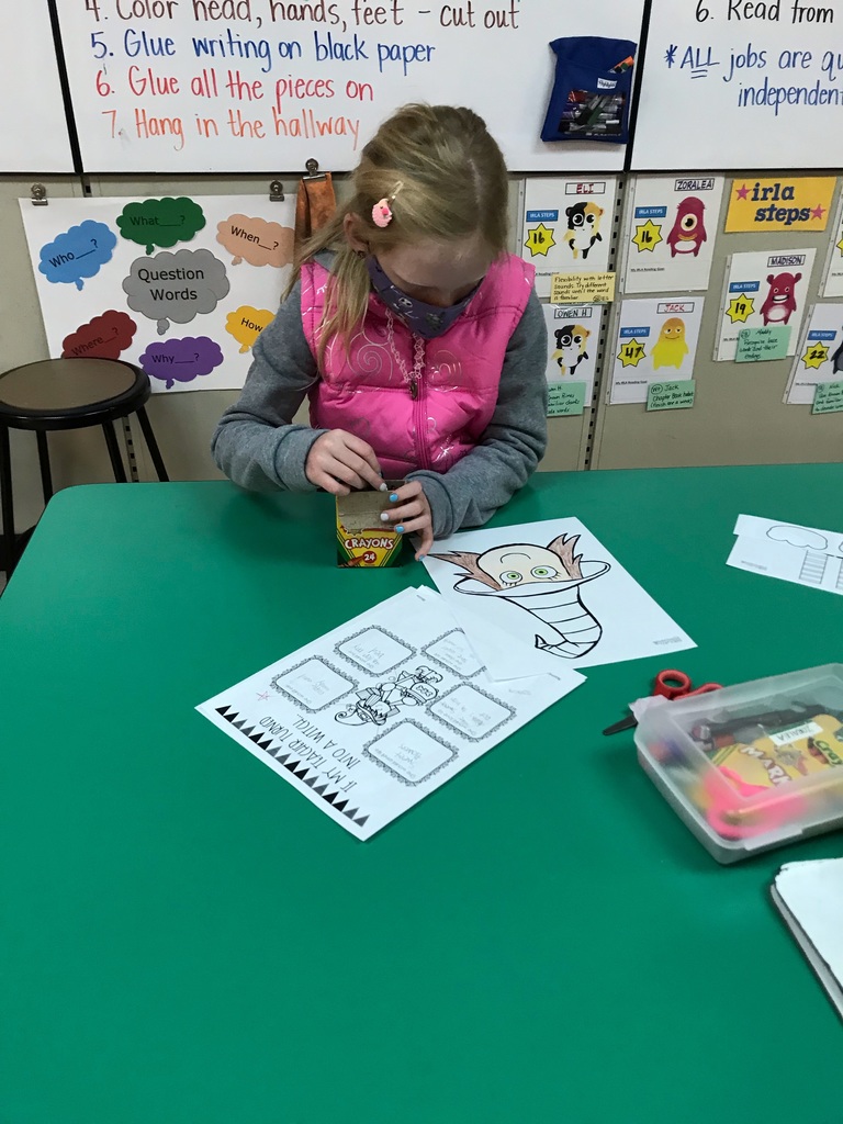 a girl in a pink vest uses crayons to work on her witch writing assignment