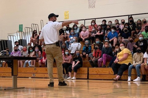 A first responder discusses fire safety with students in the Silver Creek gymnasium.