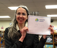 Librarian Paula Michalak holds p her Sustainable Library Certificate