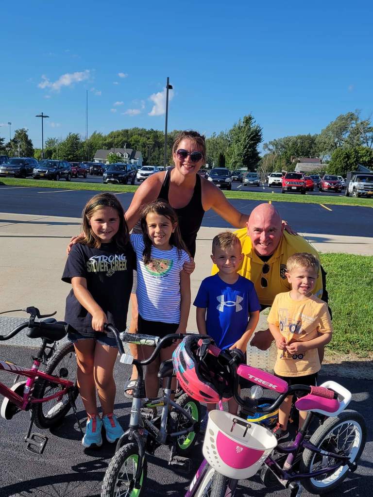 Wes Johnson and Jen Johnson pose outside with 4 kids and their bikes 