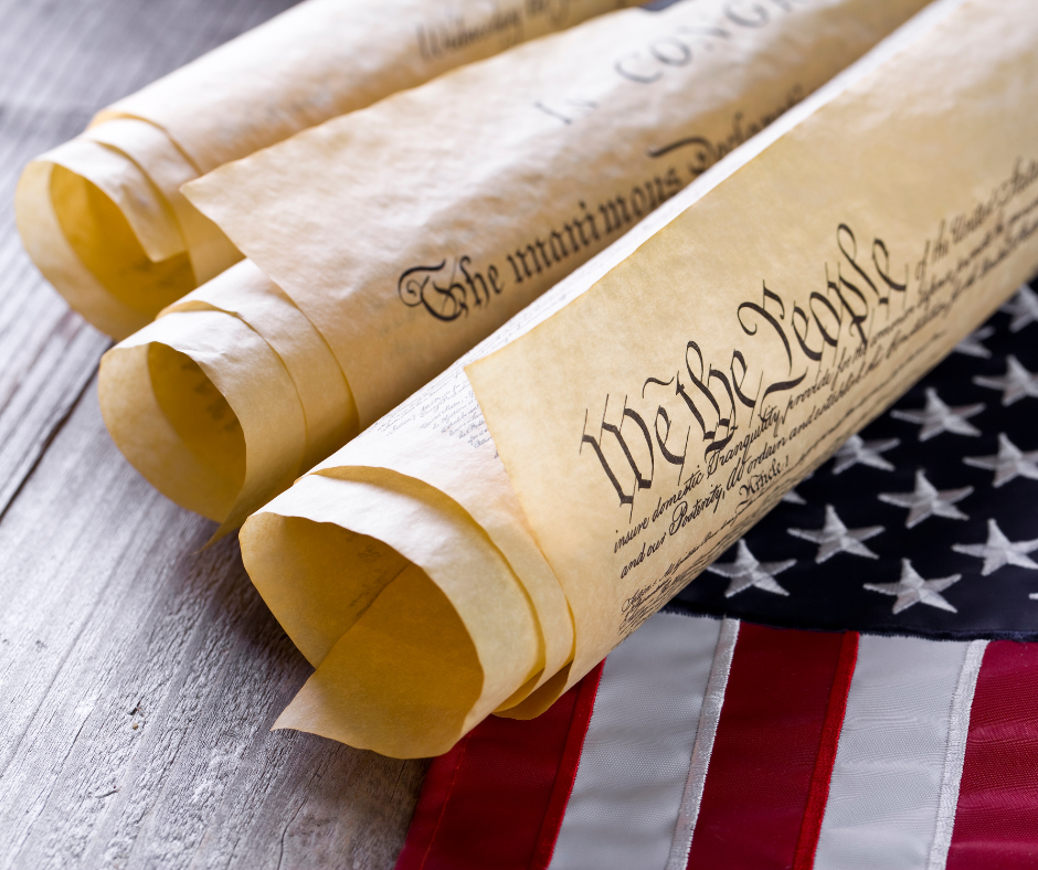 We the People on scrolls that look like the Constitution on top of a part of an American flag 