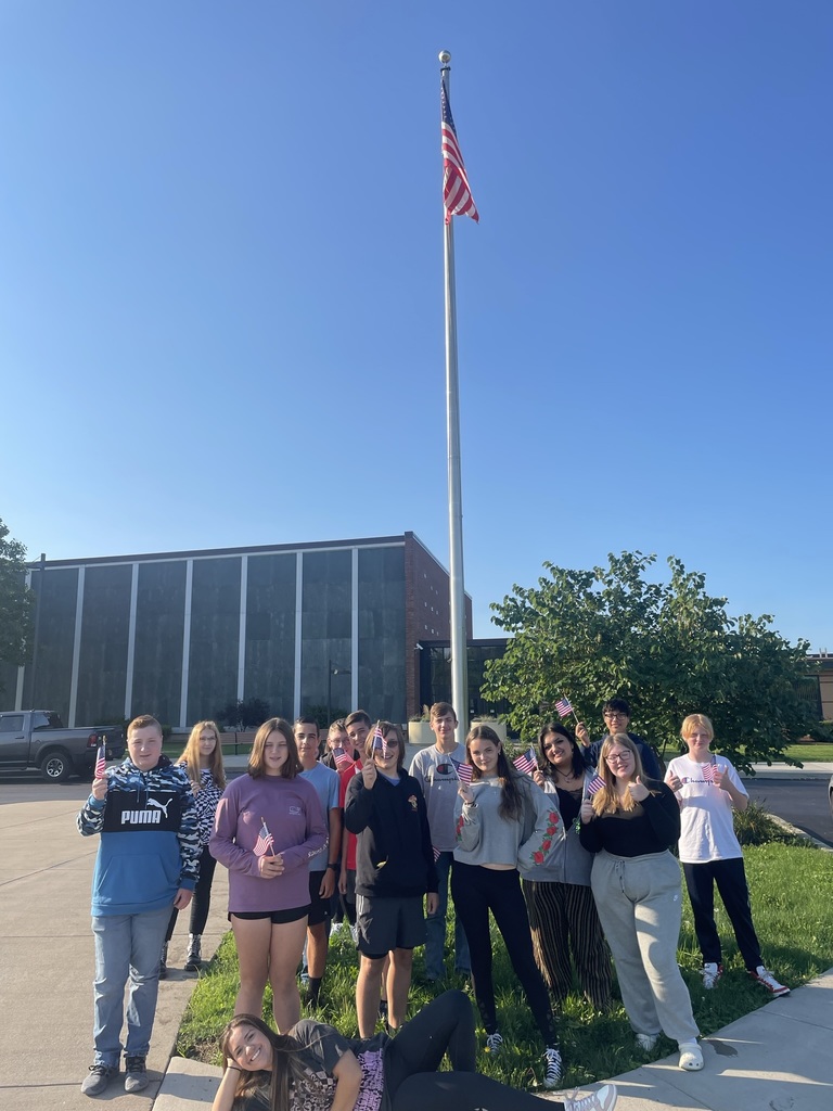Students stand in front of flag pole 