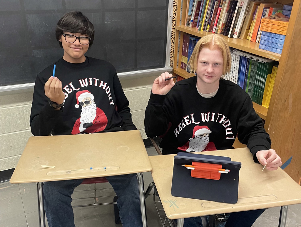 Two students sitting at desks display their cylinder seals 